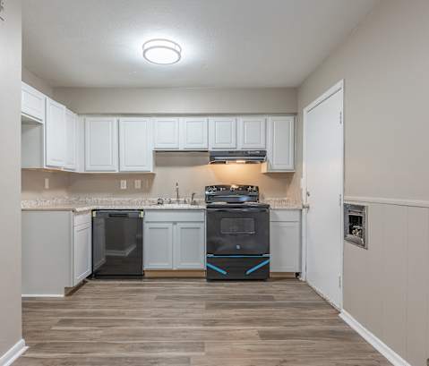 an empty kitchen with white cabinets and a black stove and oven