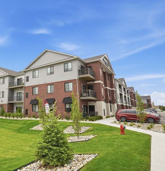 A large apartment complex with a red car parked in front.