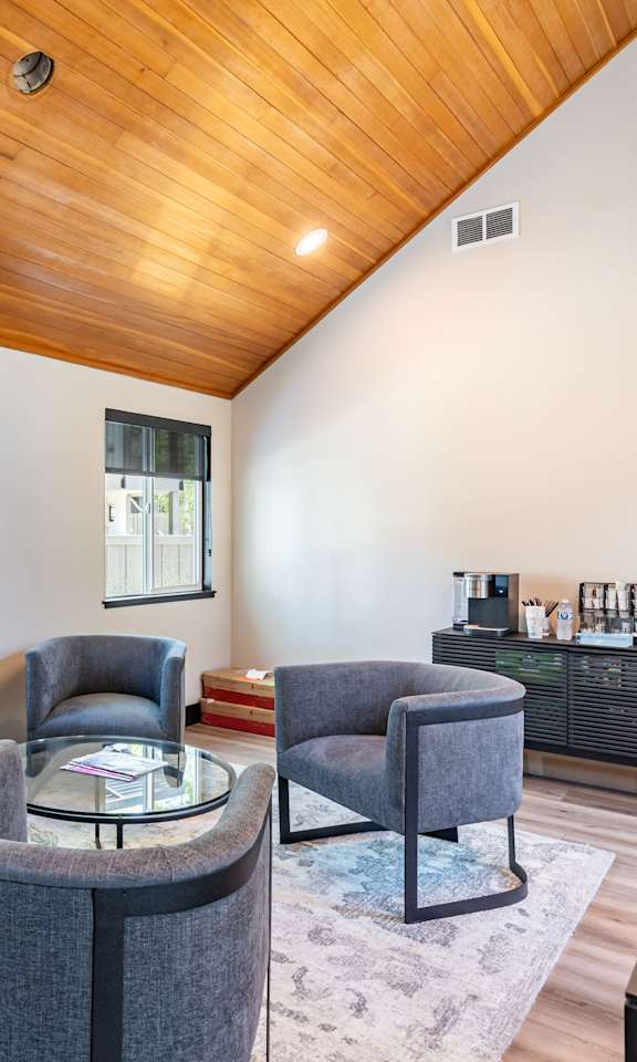 A living room with a grey sofa and a wooden ceiling.