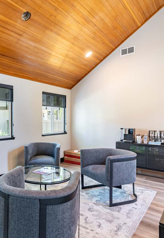 A living room with a wooden ceiling and grey chairs.