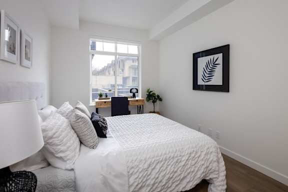 A bedroom with a large bed and a window overlooking a cityscape.