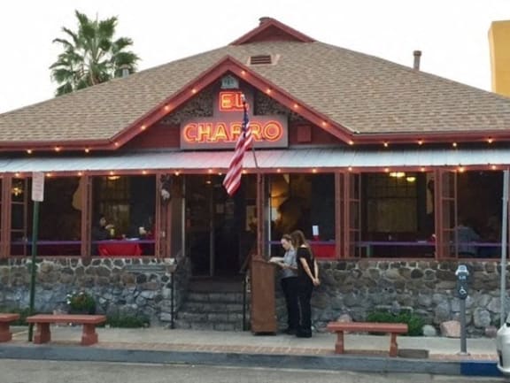 a couple of people standing outside of a charro restaurant