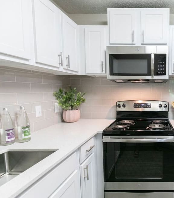 a white kitchen with stainless steel appliances and a counter top