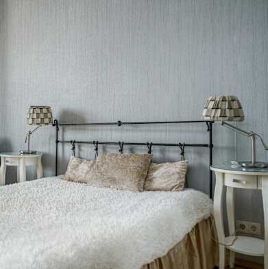 a bedroom with a bed and a chair and a table with lamps