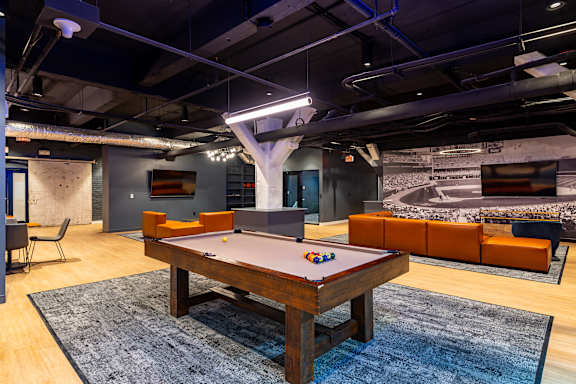 A pool table in a room with a couch and a chair.