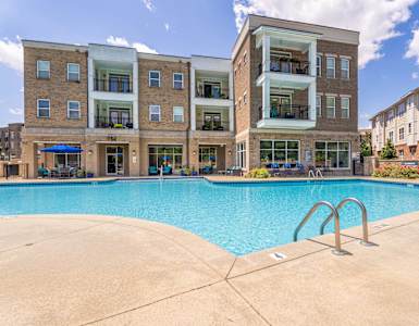 A large swimming pool in front of a multi-story apartment building.