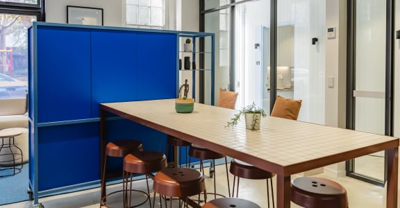 a communal table and stools in a room with glass doors