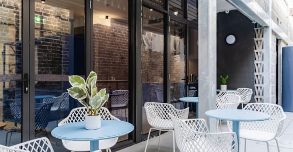 a patio with blue tables and chairs outside of a building