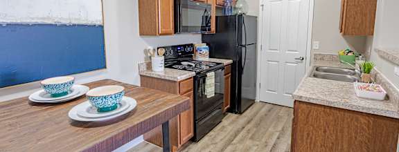 A kitchen with a refrigerator, microwave, oven, and sink.
