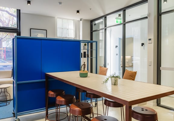 a communal table and stools in a room with glass doors