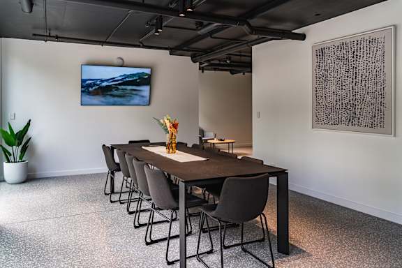 a conference room with a long table and chairs and a painting on the wall
