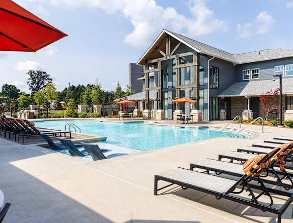 A large swimming pool with lounge chairs and a building in the background.
