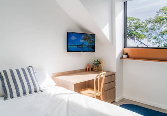 a bedroom with a bed and a desk and a window