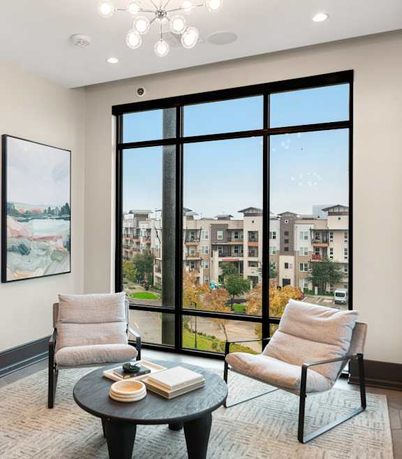 A living room with a large window and two chairs.