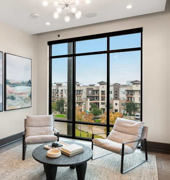 A living room with a large window and two chairs.