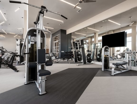 a gym with weights machines and a tv on the wall  at Encore at Boulevard One, Colorado, 80230