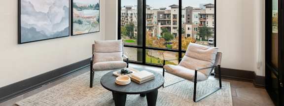 A living room with a large window and two chairs.