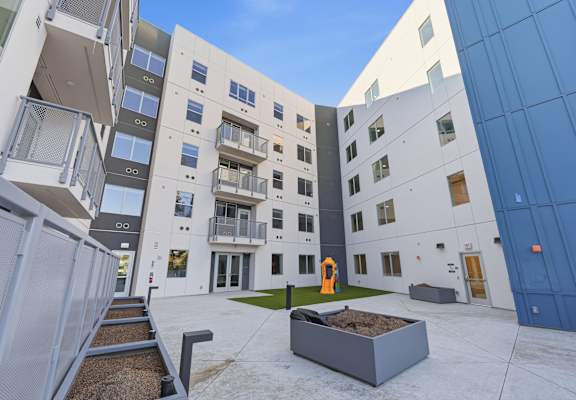 A courtyard with a sandbox and a building with balconies.