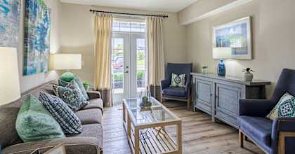 A living room with a grey couch, a blue chair, and a wooden coffee table.