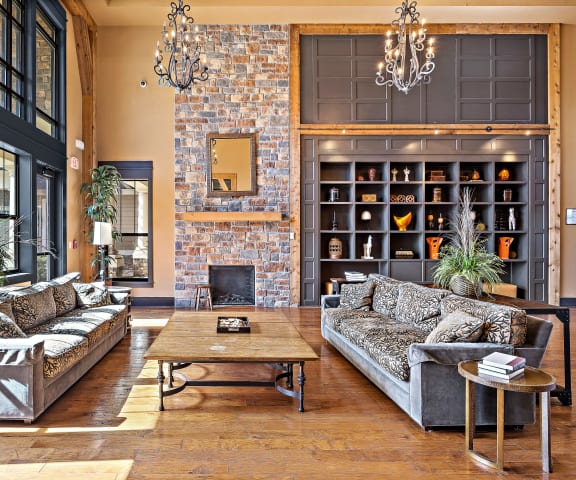 a living room with couches and a coffee table in front of a brick fireplace
