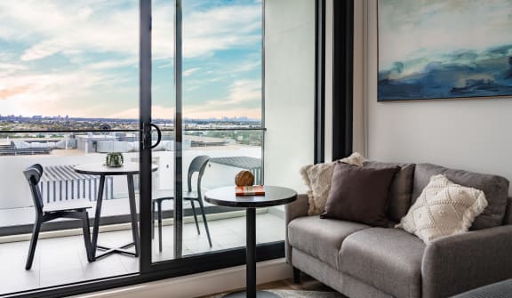 a living room with a couch and a table overlooking a balcony