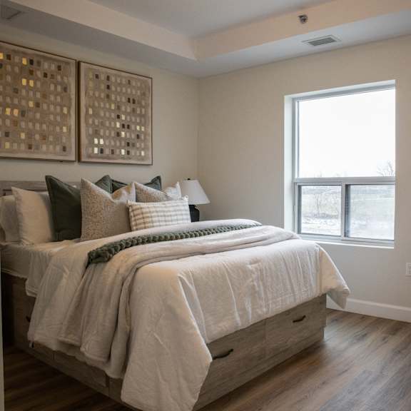 a bedroom with a bed and a nightstand with a lamp and flowers