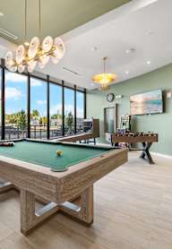 A pool table in a room with a green wall and a TV.