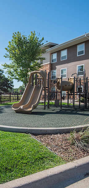 A playground with a slide and a building in the background.