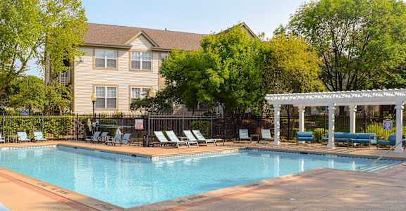 a swimming pool with chairs and a building in the background