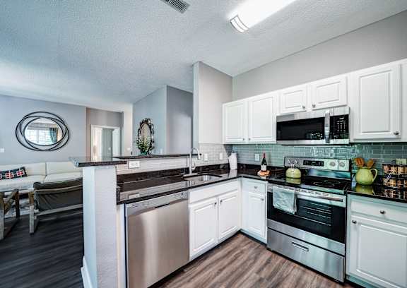 A modern kitchen with white cabinets and stainless steel appliances.