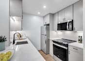 Thumbnail 23 of 25 - A modern kitchen with a refrigerator, oven, and sink.