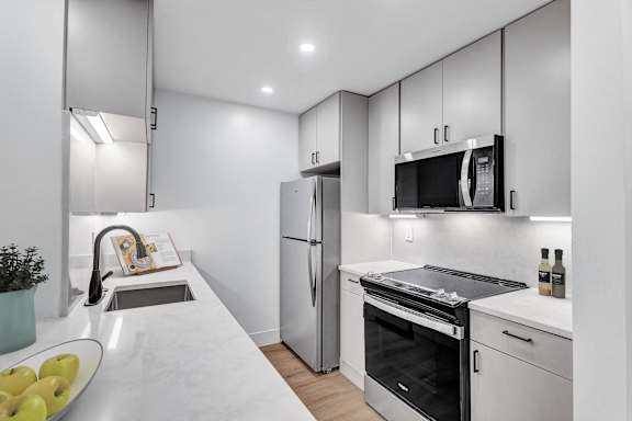 A modern kitchen with a refrigerator, oven, and sink.