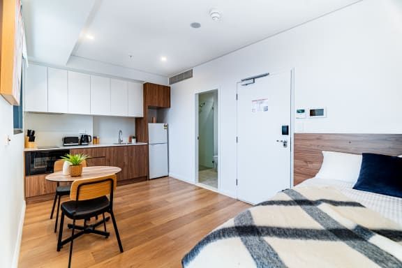a bedroom with a bed and a kitchen with a small table