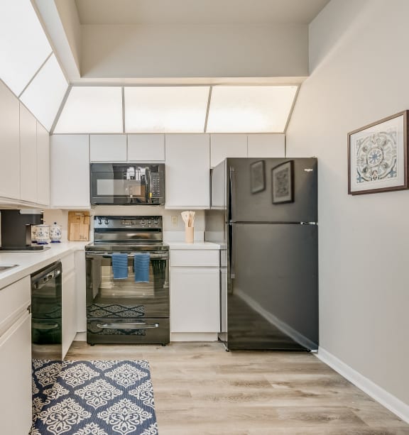 a kitchen with white cabinets and stainless steel appliances and a black refrigerator