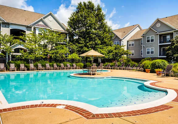 A swimming pool surrounded by a brick border and chairs.