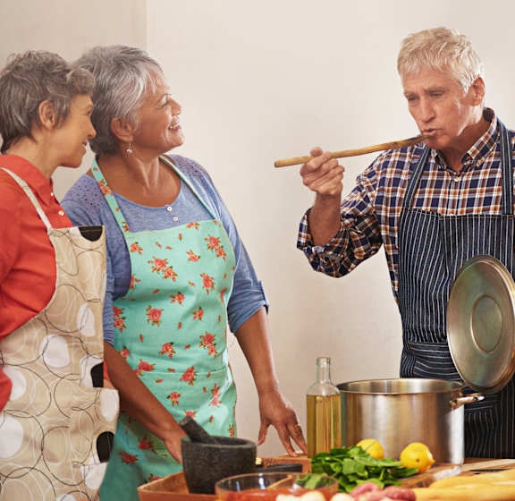 A group of people wearing aprons cooking together.
