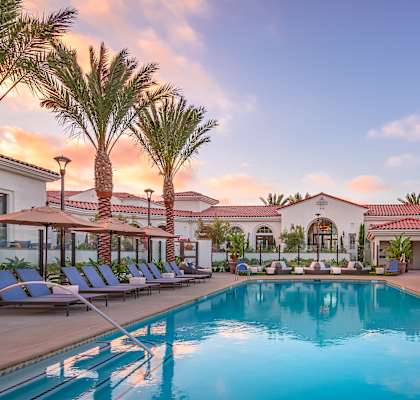 a resort style swimming pool with lounge chairs and umbrellas