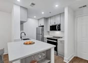 Thumbnail 1 of 25 - A modern kitchen with white cabinets and appliances.