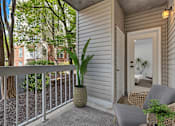 Thumbnail 24 of 25 - A balcony with a chair and a potted plant.