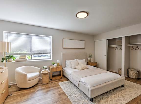 A bedroom with a large bed, a chair, and a nightstand.