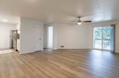 an empty living room with a ceiling fan