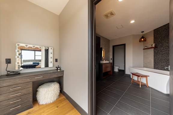 A bathroom with a white tub and a wooden stool.