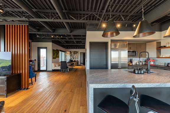 the kitchen and living room of a modern house with wood floors and a gray counter