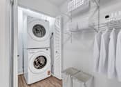 Thumbnail 7 of 25 - A white laundry room with a washer and dryer stacked on top of each other.