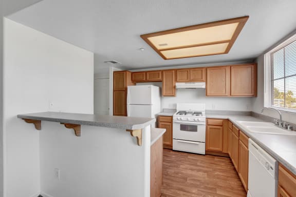 a kitchen with wood cabinets and white appliances at Aspen Peak, Henderson