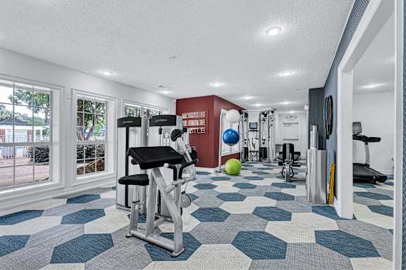 A gym with a variety of equipment including a weight bench, exercise ball, and treadmill.