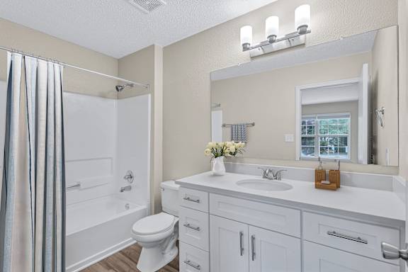A white bathroom with a toilet, sink, and shower.