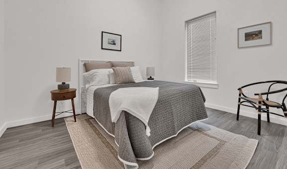 a bedroom with white walls and a bed with gray blankets