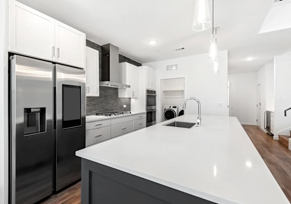 A modern kitchen with a white countertop and stainless steel appliances.
