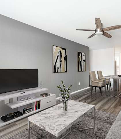 A modern living room with a grey sofa, a white coffee table, and a television.